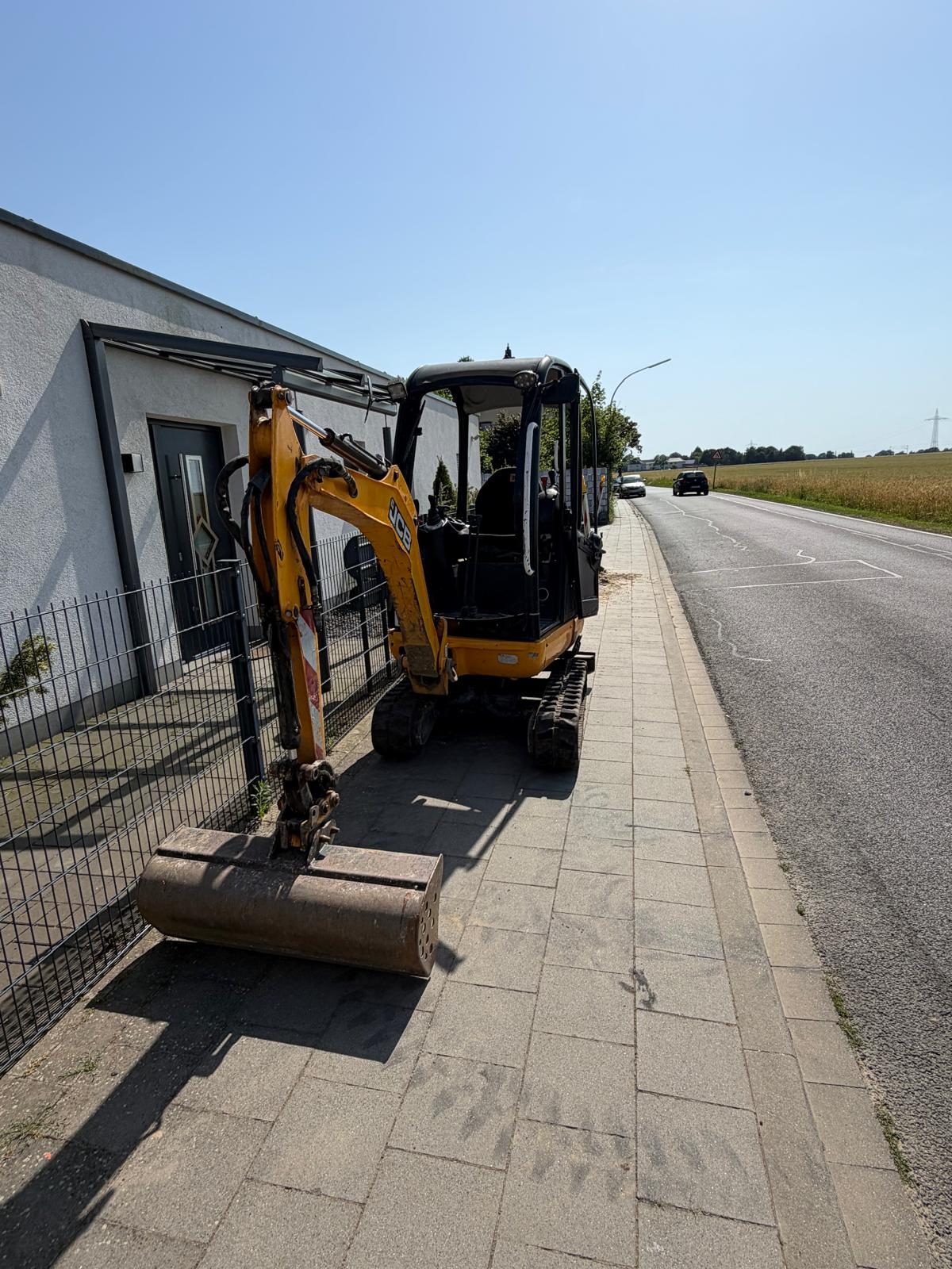 Minibagger von Galabau Premio im Einsatz am Gehweg vor einem Wohnhaus