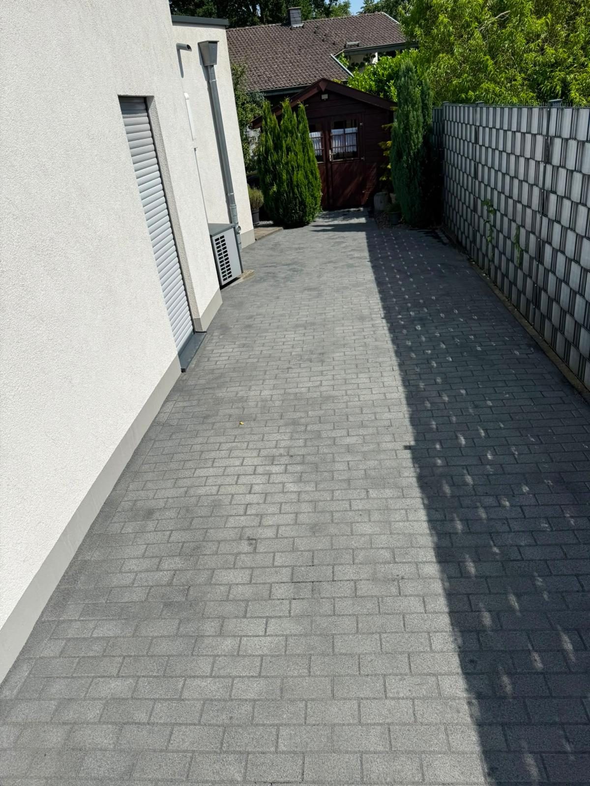 Nachher: gepflasterter Seitenstreifen mit Sichtschutz und Gartenhaus