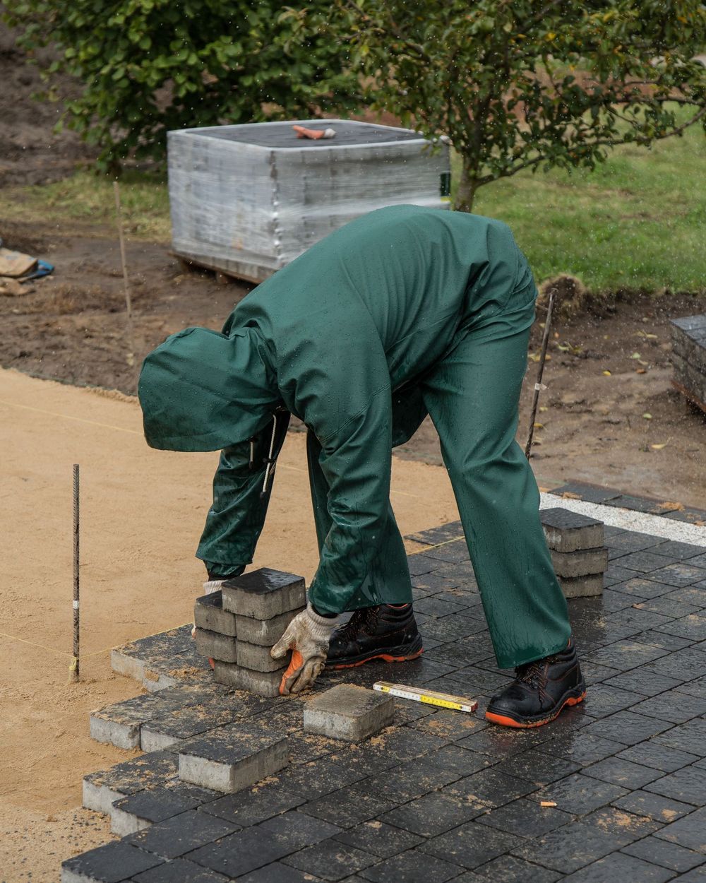 Pflasterer in Arbeitskleidung verlegt Betonsteine