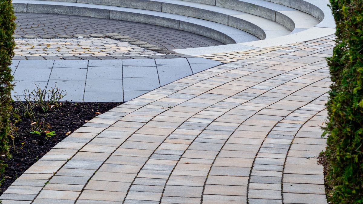 Geschwungener Klinkerweg führt zu einem tiefer gelegten Sitzplatz im Garten